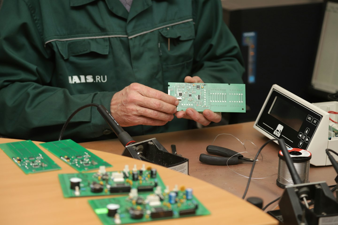 Engineer examines circuit board with microchips on workbench.