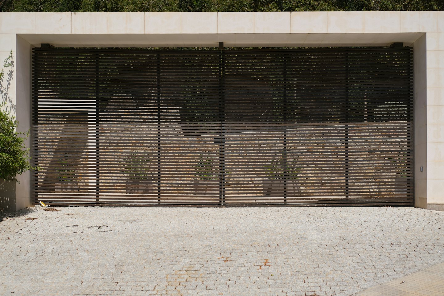 Modern dark metal gate set in a light stone entrance.